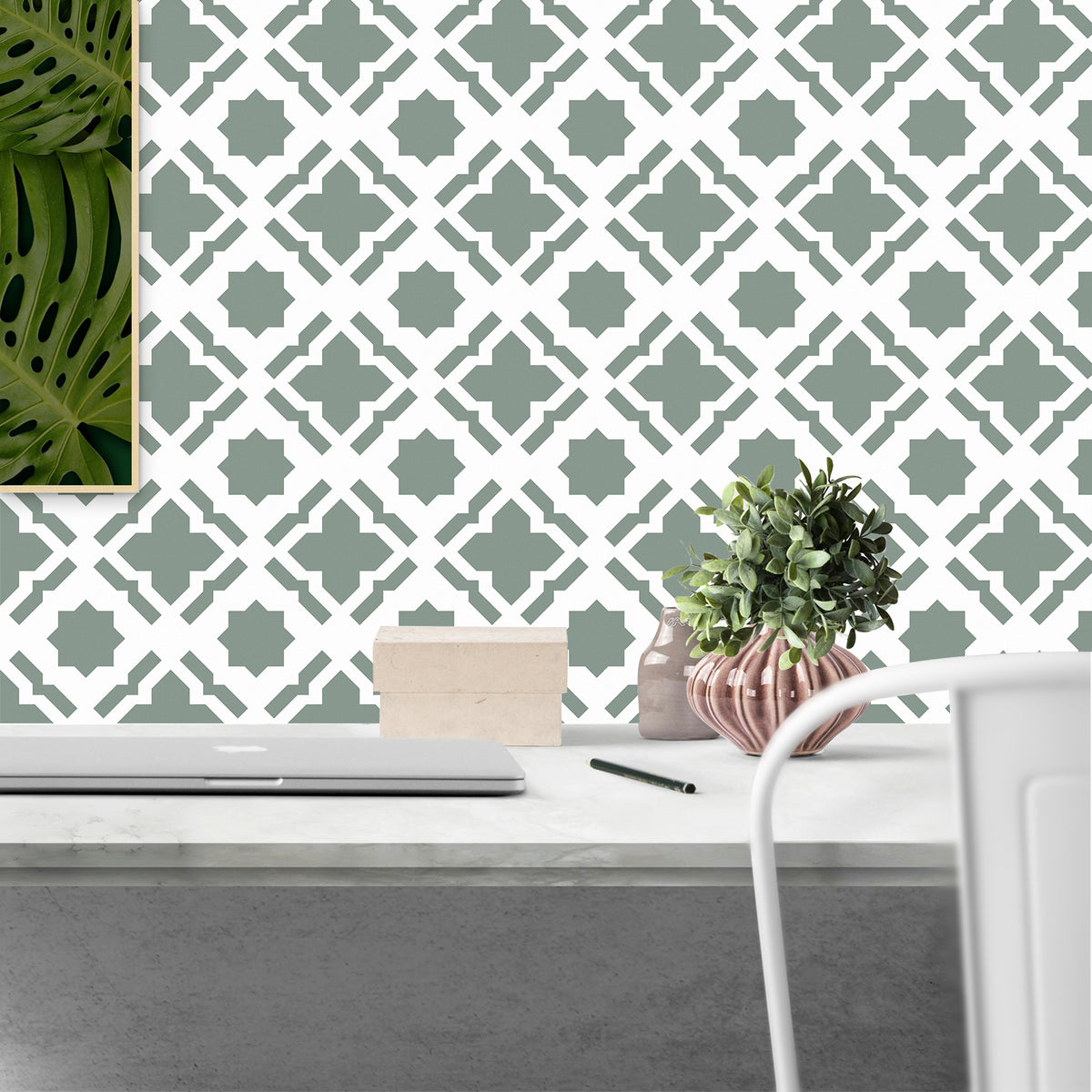 Decorative wall with geometric pattern, desk with laptop, and plants.