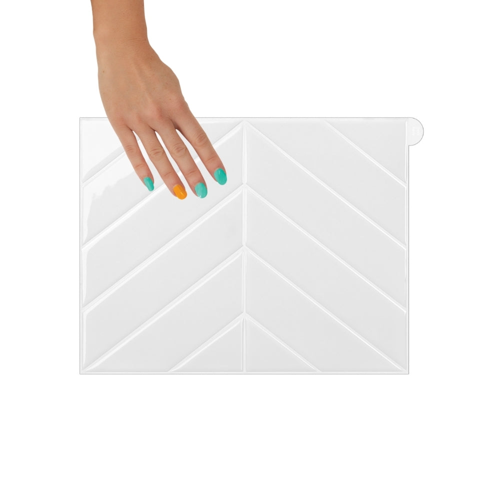 Bathroom vanity with wooden cabinets, white countertop, and chevron-patterned white tiles on the wall.