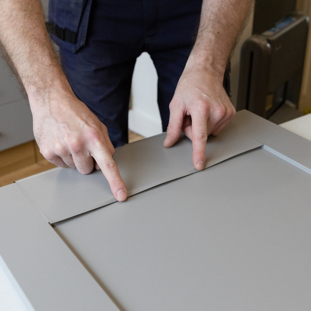 Adhesive vinyl being applied to a kitchen cupboard