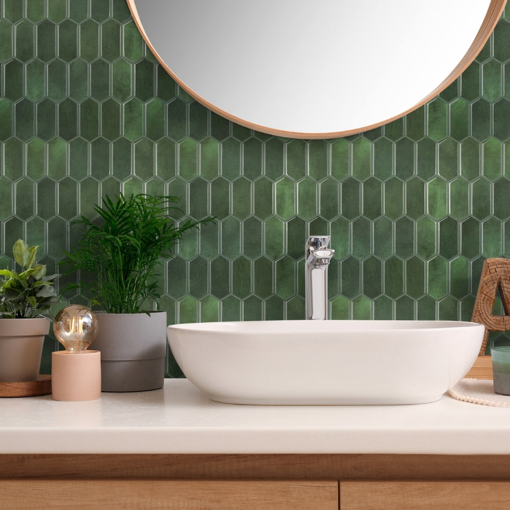 Bathroom vanity with a white sink, green tiled wall, and decorative items.