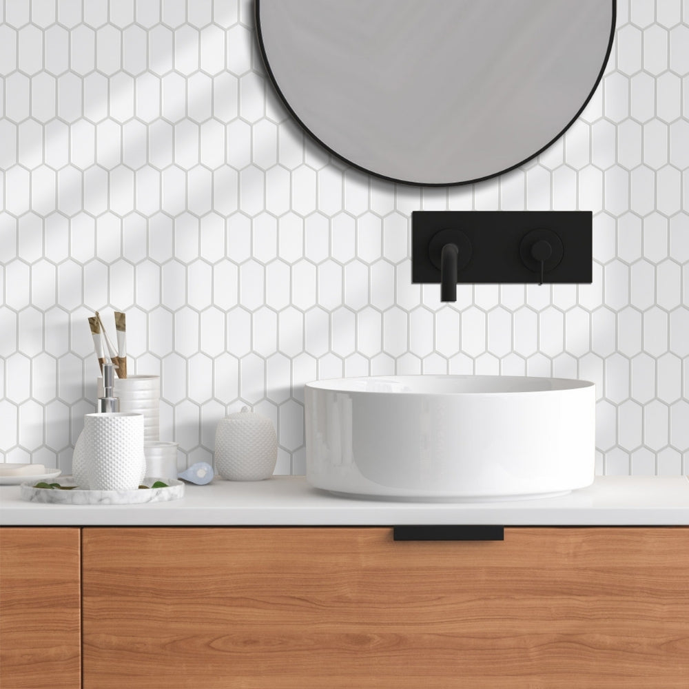 Bathroom with hexagonal white tiles, wooden vanity, and round mirror.