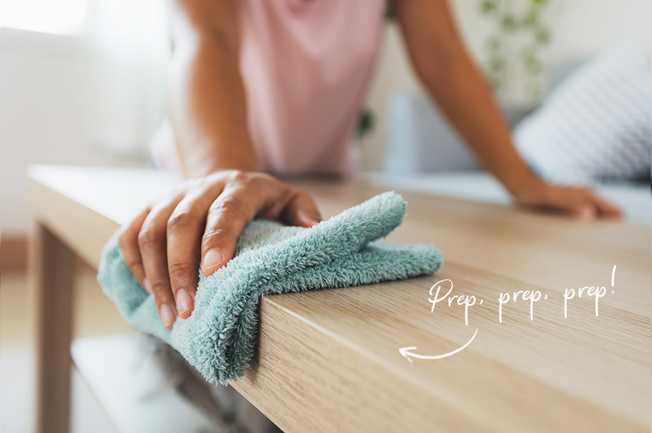 Woman in pink shirt dusting a wood grain table with mint green cloth, text saying Prep, prep, prep!