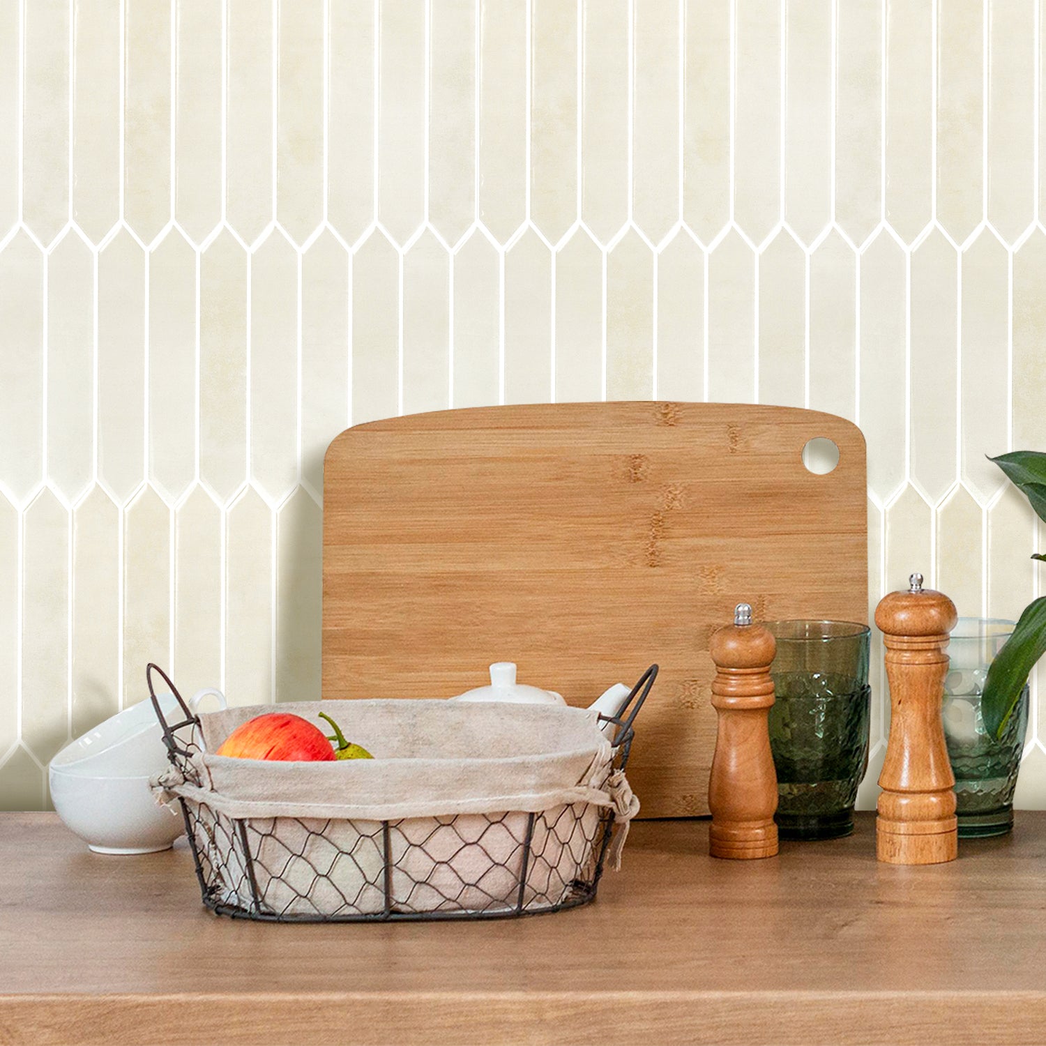 Wooden cutting board, basket with produce, and salt and pepper shakers on a kitchen counter.