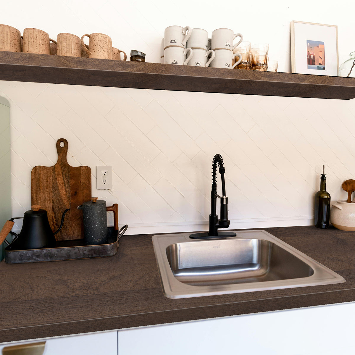 Kitchen sink area with wooden shelves, mugs, and a faucet.