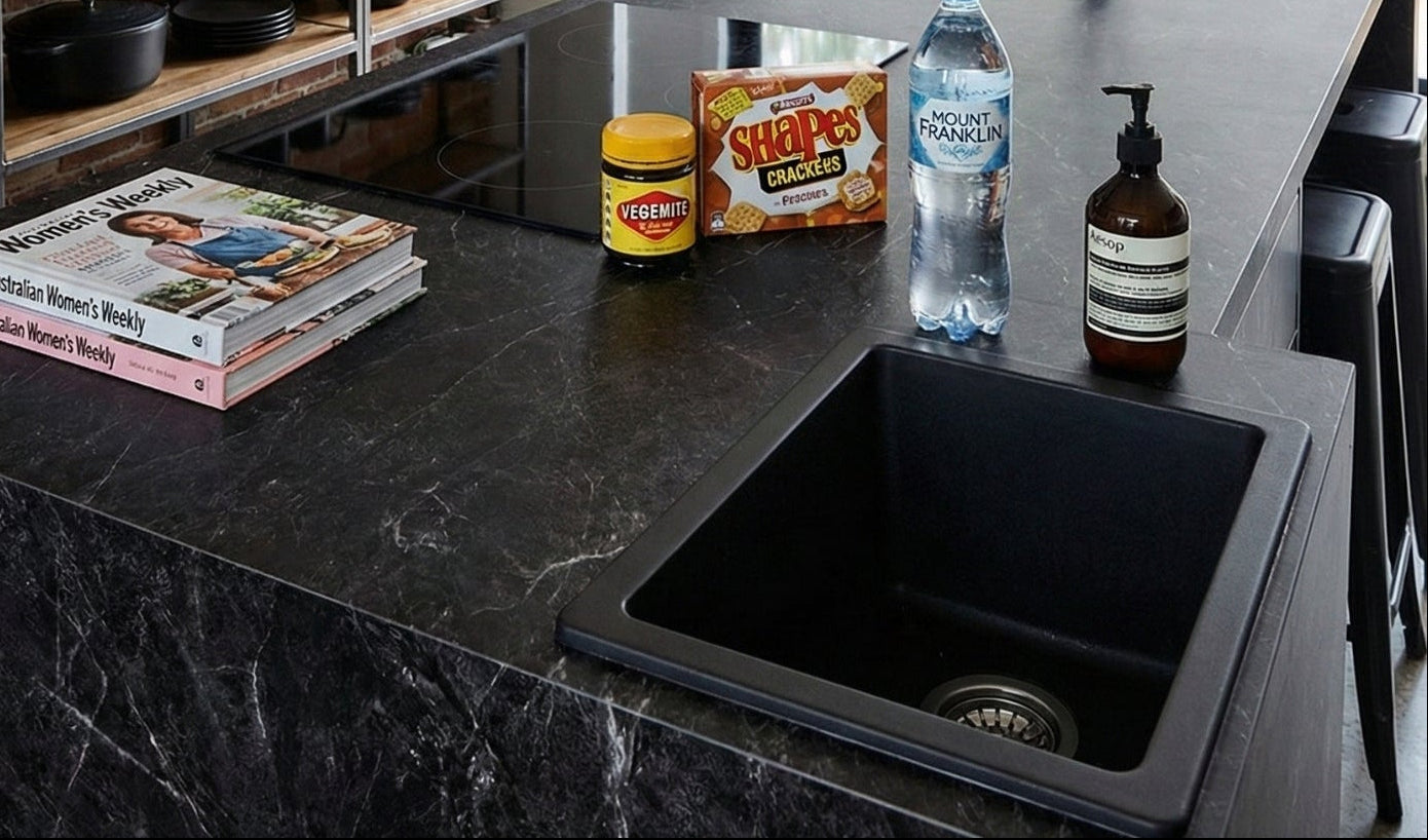Modern kitchen with black countertops, sink, and shelves against a brick wall.