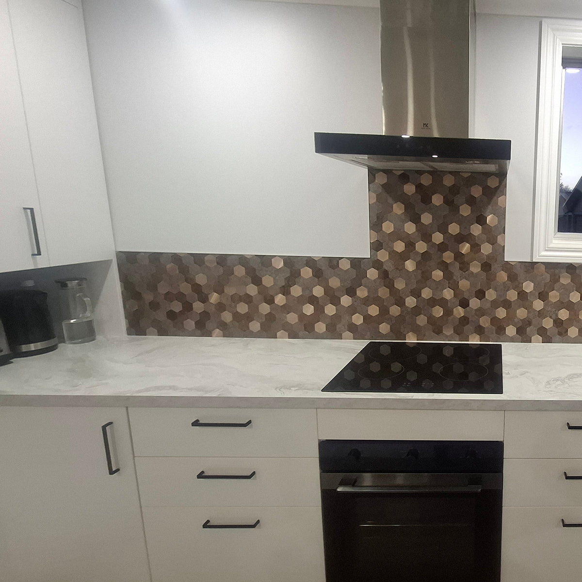 Modern kitchen with white cabinets, black appliances, and a patterned backsplash.