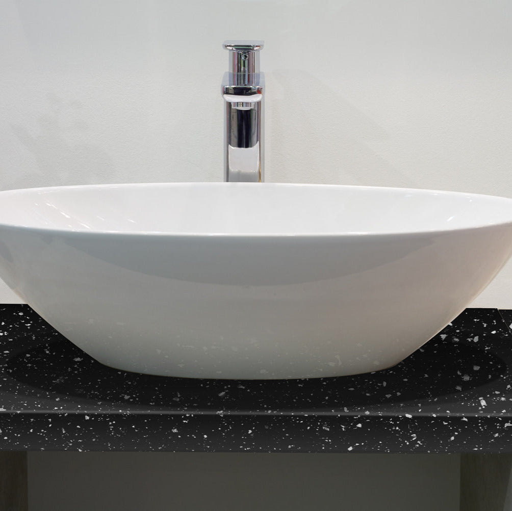 White oval sink on a black speckled countertop with a gray background