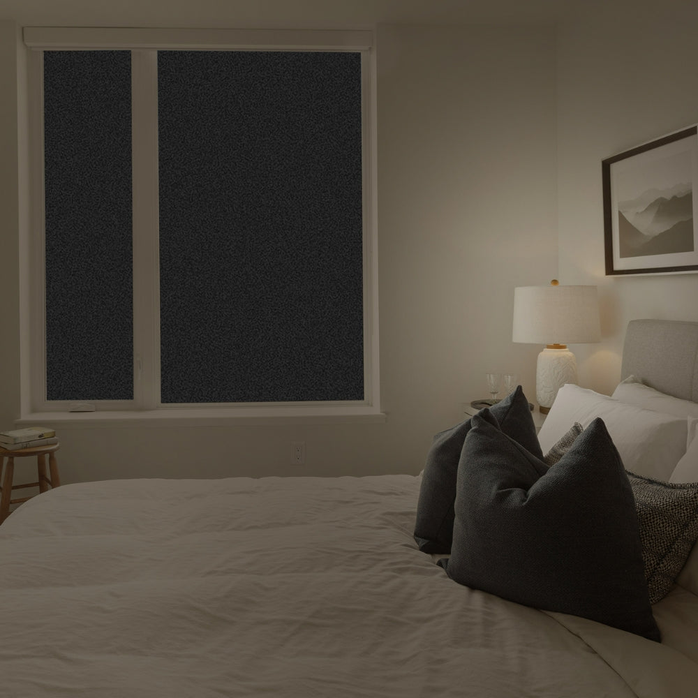 Bedroom with a bed, lamp, and window with blackout window film.