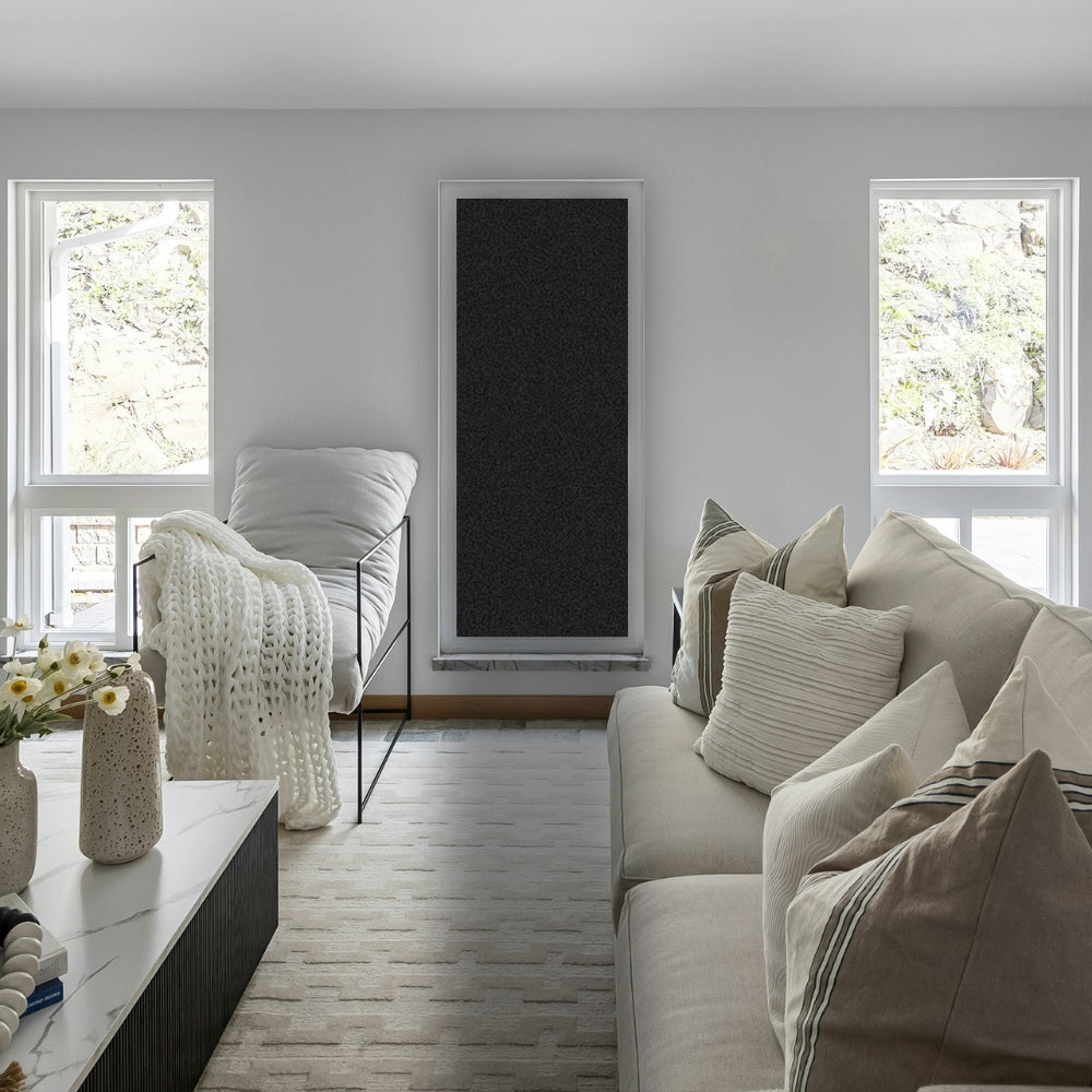 Modern living room with a sofa, armchair, and decorative elements and a widow with blackout window film.