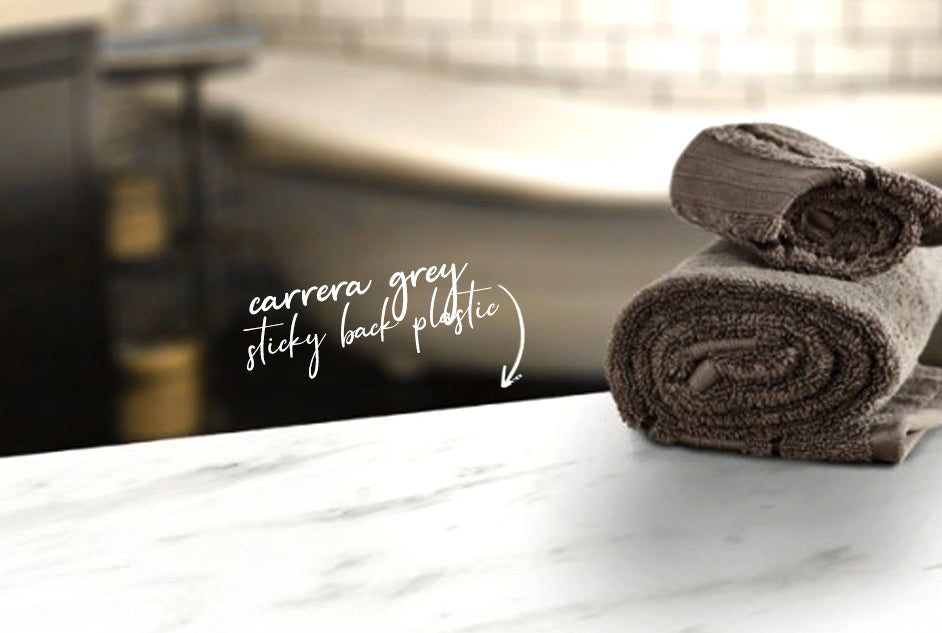 Carrara grey vinyl on bench top in bathroom with small towels on top and white bathtub in background