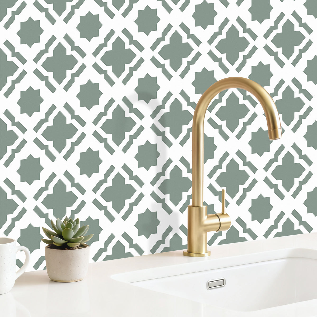 Gold faucet on a kitchen sink with decorative wall pattern
