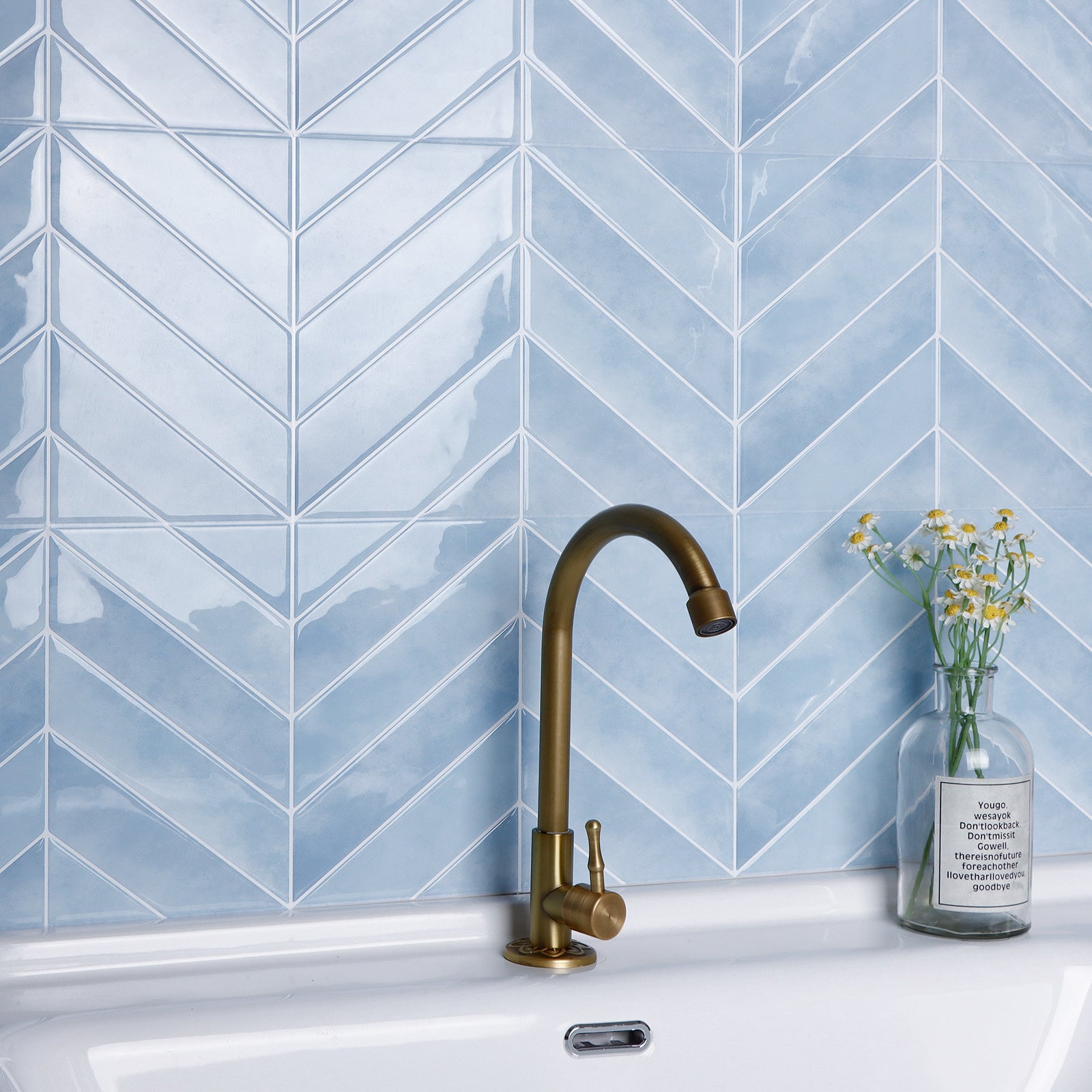 Kitchen sink with a gold faucet against a blue tiled wall