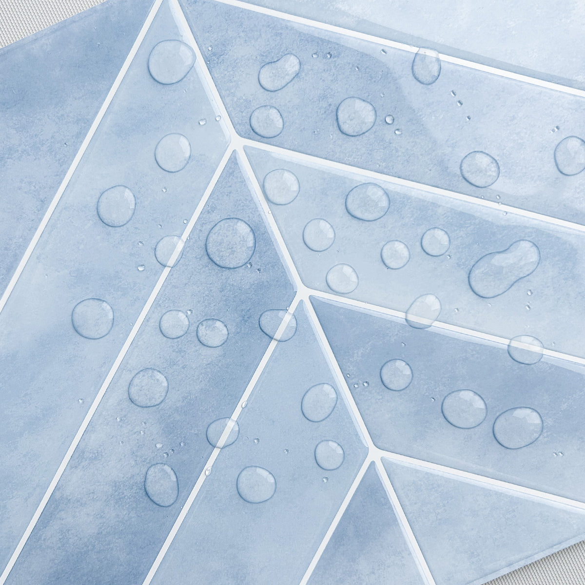 Geometric pattern of blue tiles with water droplets on a textured surface