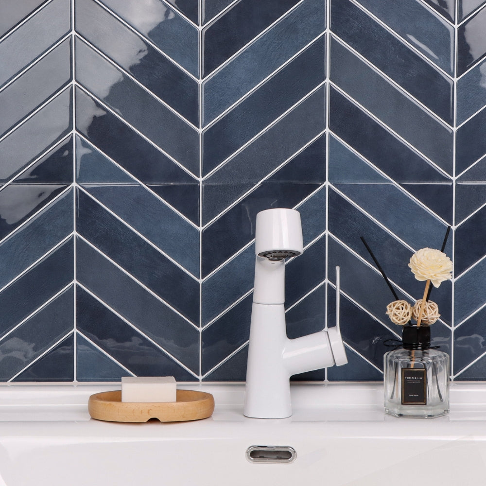 White faucet on a sink with blue chevron tiled wall