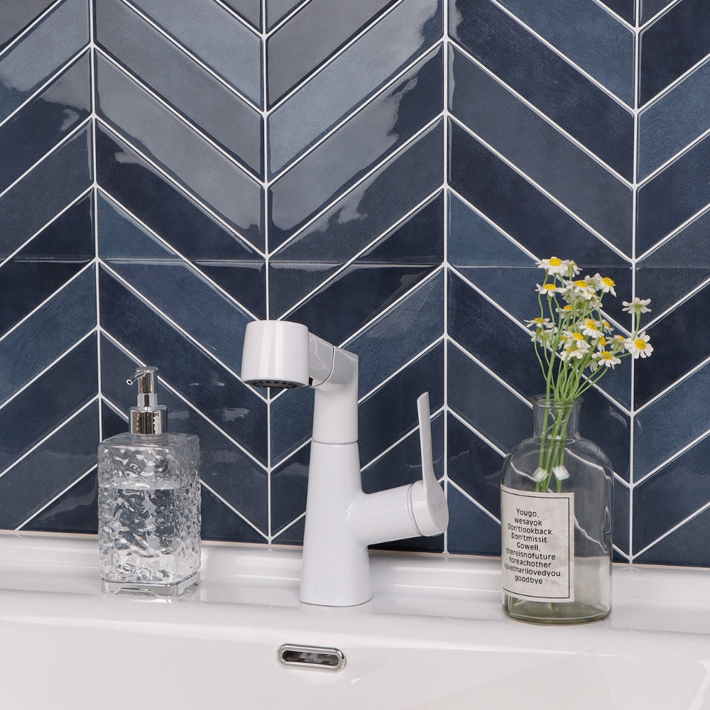 Bathroom sink with white faucet, soap dispenser, and vase with flowers against a blue tiled wall.