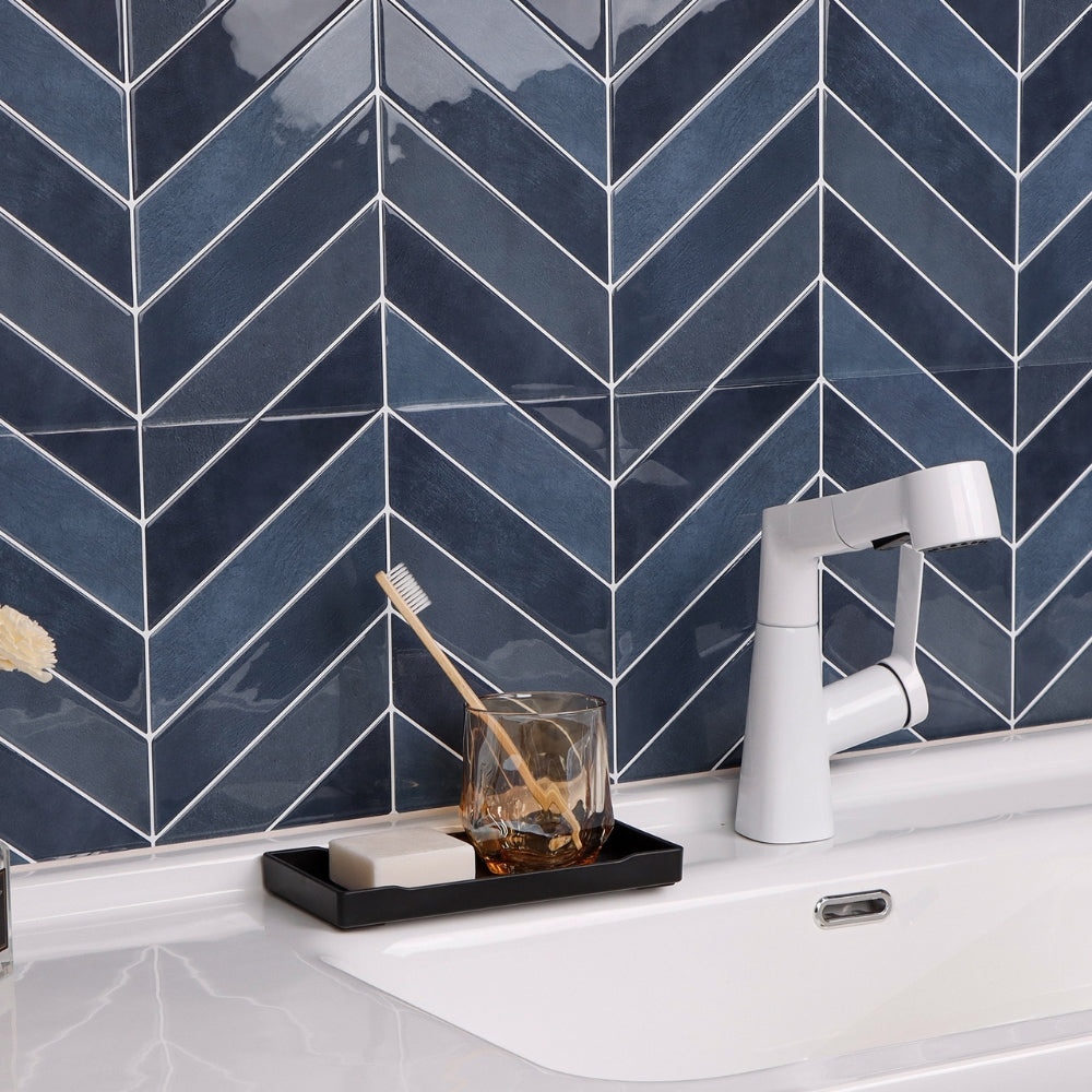 Modern kitchen sink with white faucet against a blue tiled wall