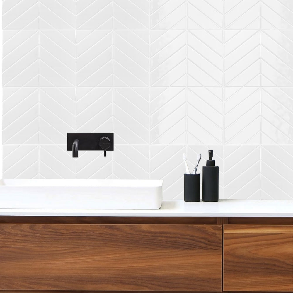 Bathroom vanity with wooden cabinets, white countertop, and chevron-patterned white tiles on the wall.