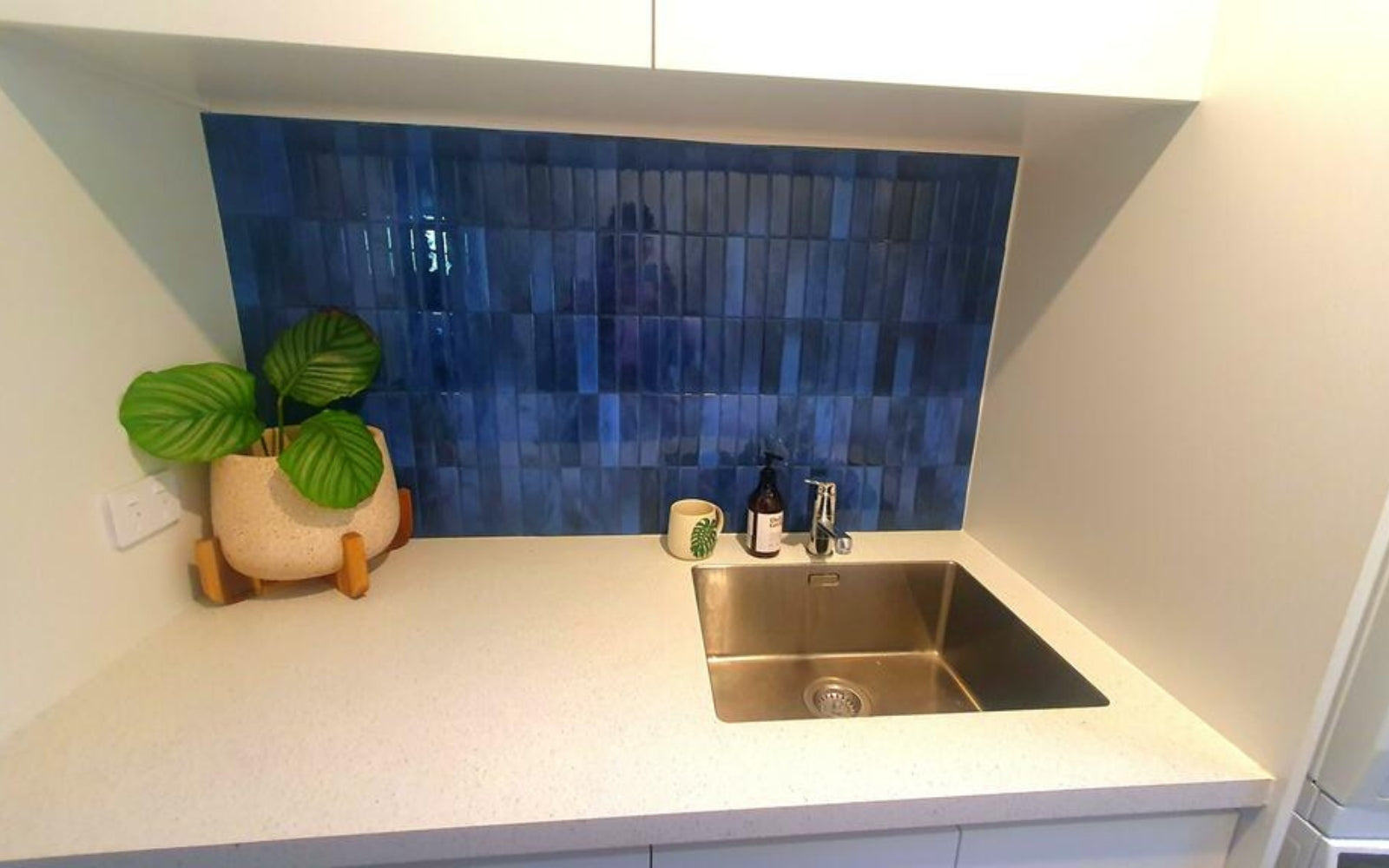 laundry sink area with blue tiles backsplash and white countertop