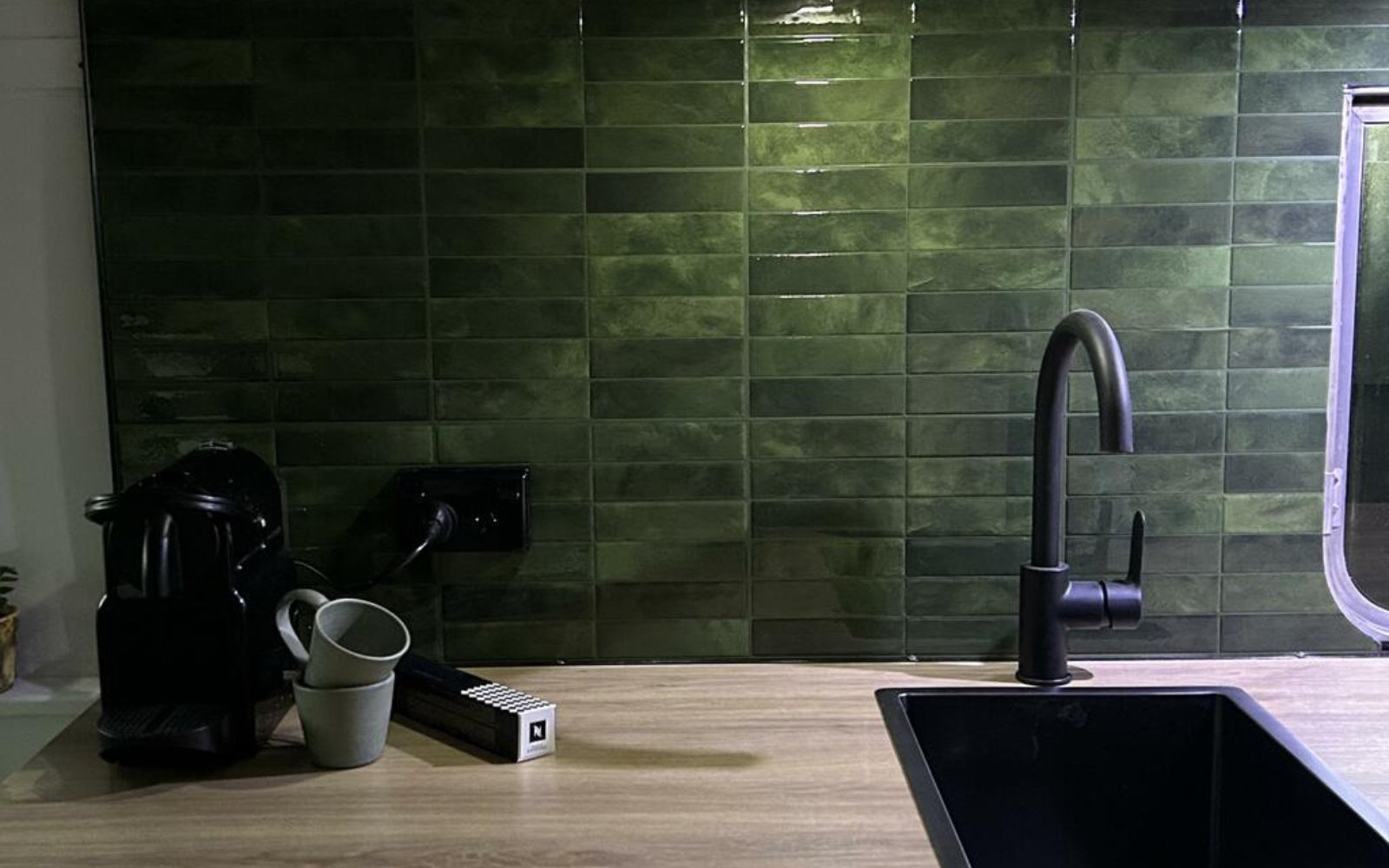 Kitchen with peel and stick green tiled backsplash and wooden countertop in a caravan