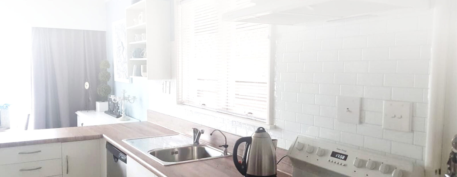 Kitchen with white cupboards, oak wood grain vinyl wrapped bench tops and white Metro Campagnola peel & stick vinyl tiles