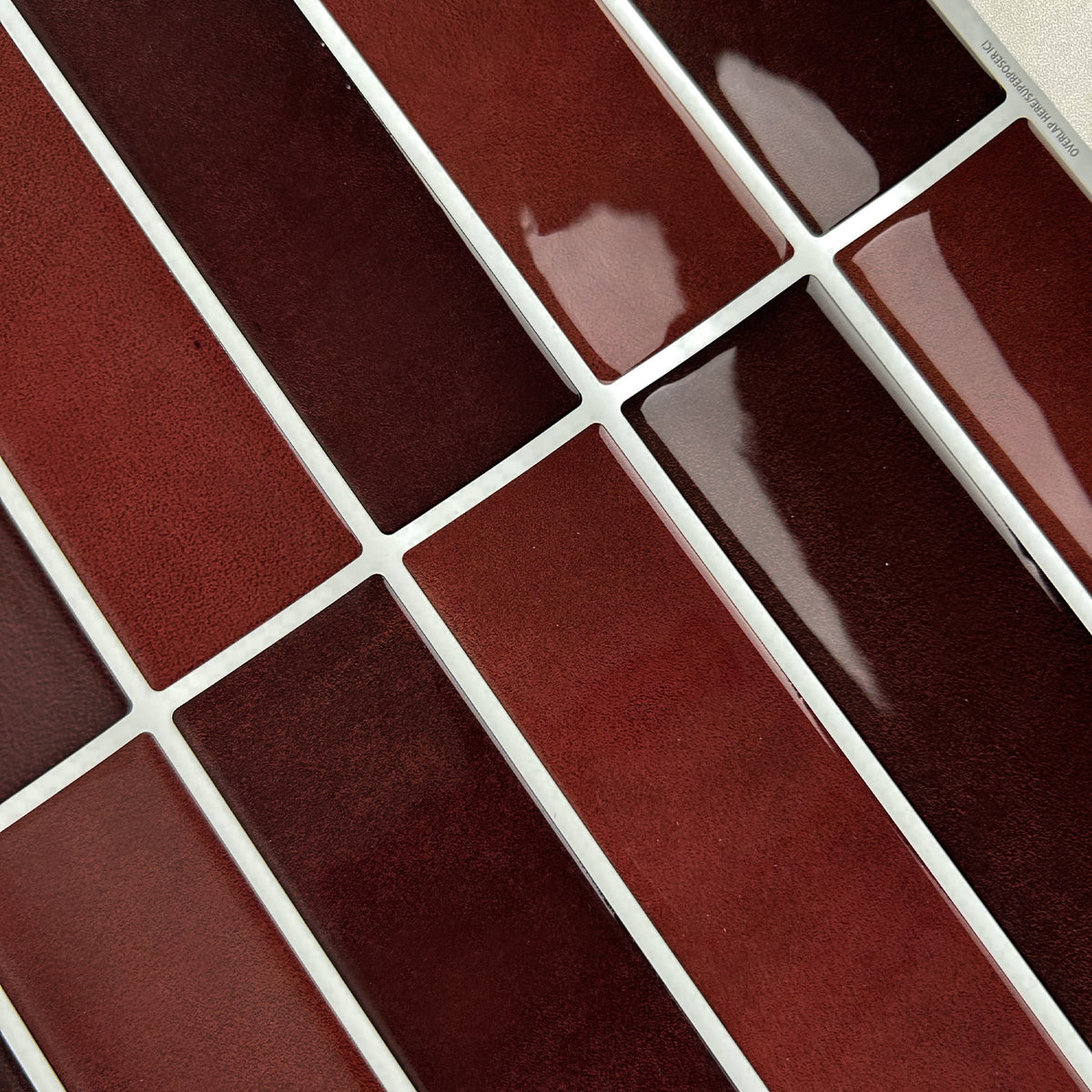 Close-up of burgundy peel and stick kit kat tiles with white grout