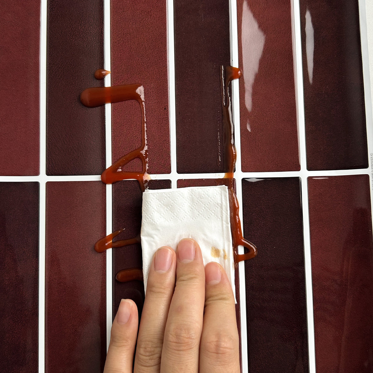 Hand using a cloth to clean a tile.