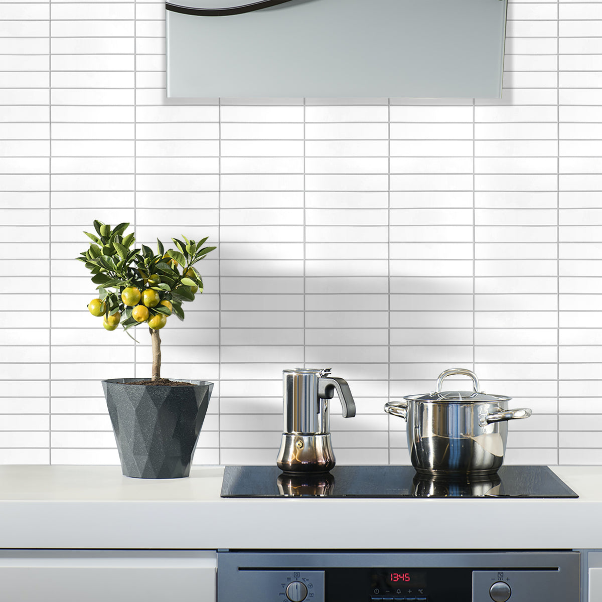 Modern kitchen with a plant, coffee maker, and pot on a stove against a tiled wall.