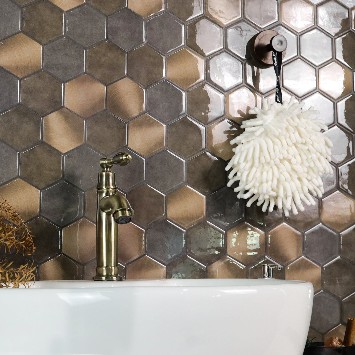Bathroom with hexagonal metallic tiles, white sink, and gold faucet.