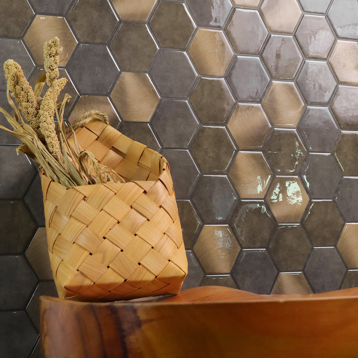 Woven basket with dried plants against a hexagonal tile wall.