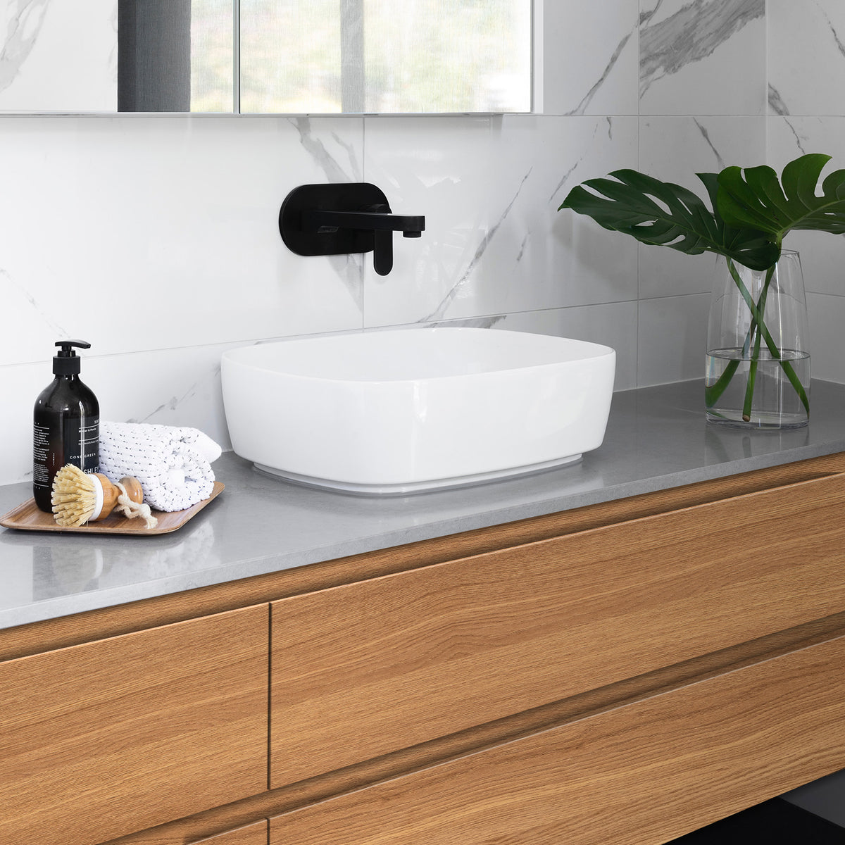 Bathroom vanity with white sink, wooden cabinets, and decorative items.