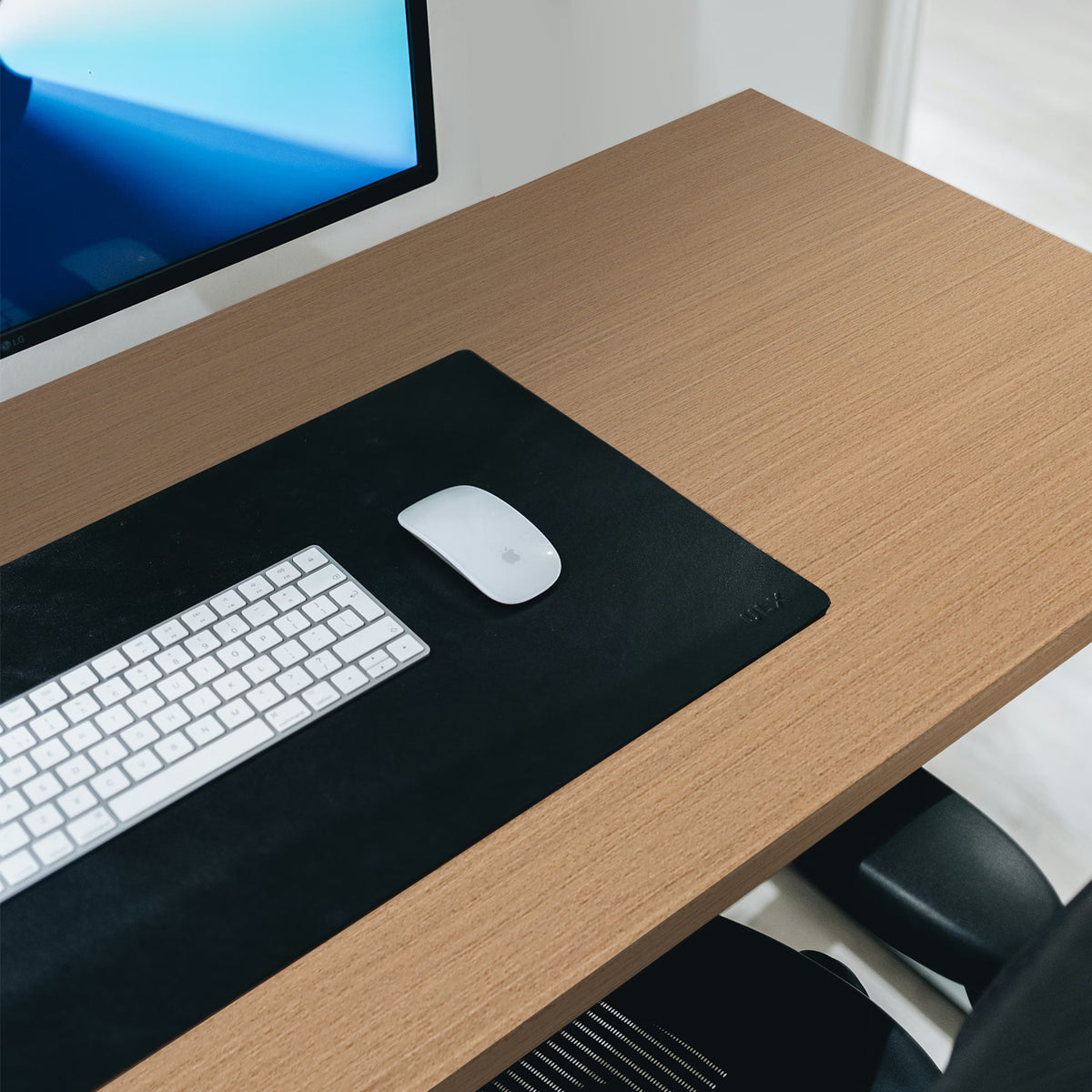 Wooden adhesive vinyl wrapped desk with computer setup including monitor, keyboard, mouse, and chair.
