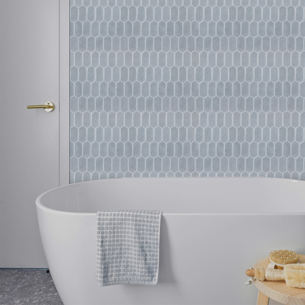 Bathroom with a white freestanding bathtub against a blue wall with geometric pattern