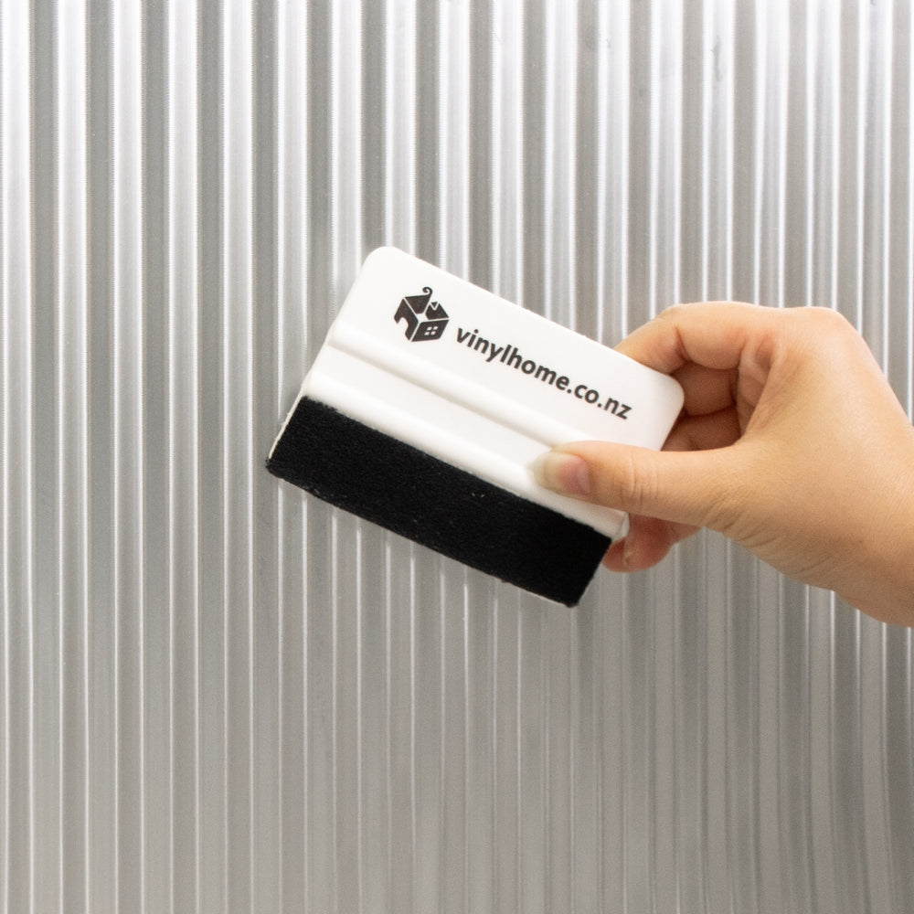 Bathroom with a window covered by reeded window film, towels on a counter, and a washing machine.