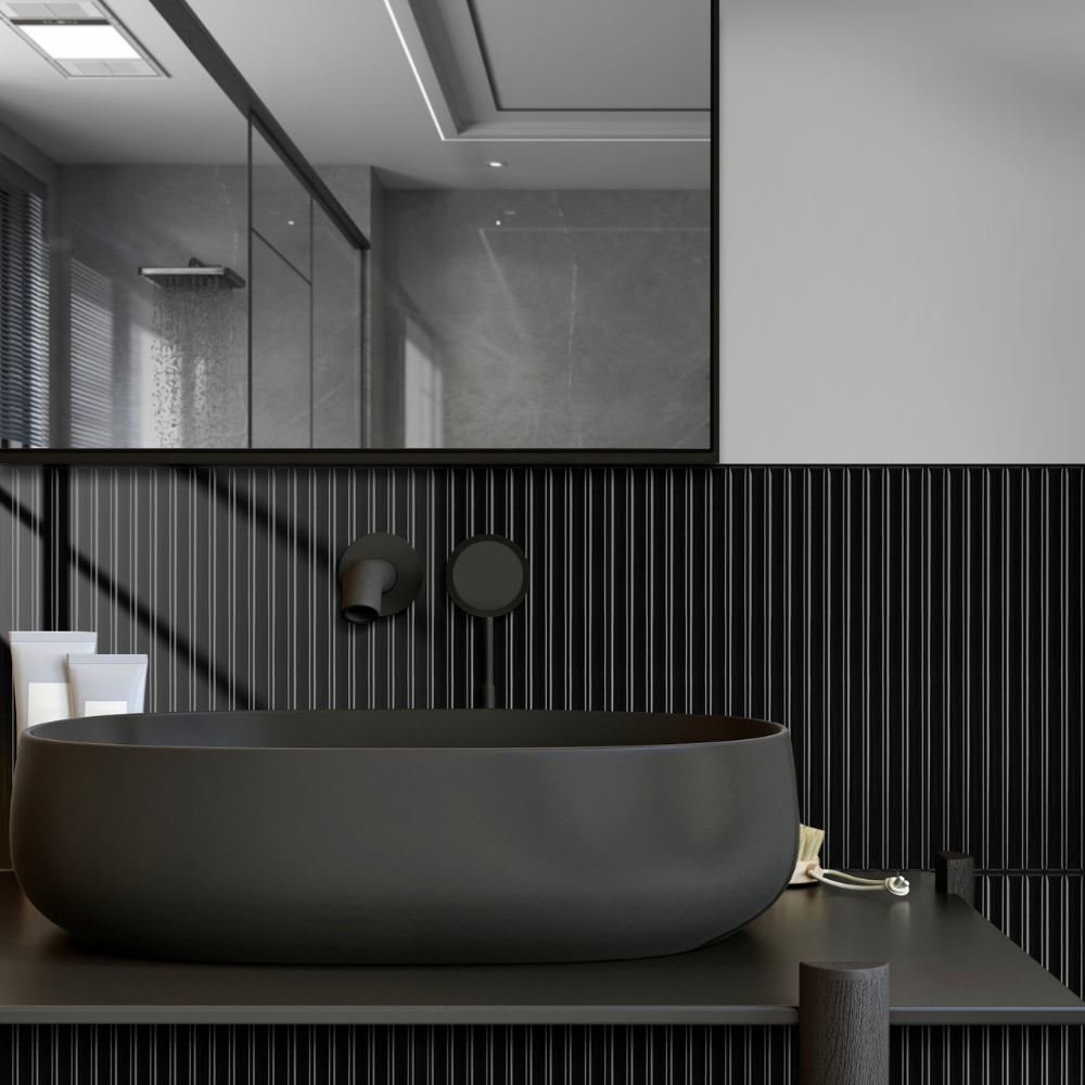 Modern bathroom with a black freestanding bathtub against a black tiled wall.