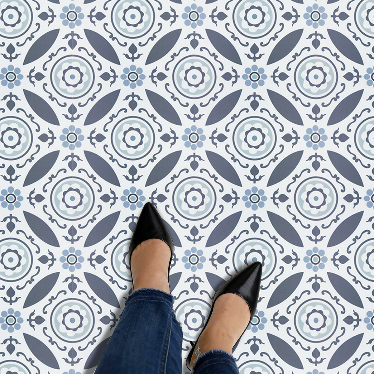 Person wearing black shoes and blue jeans standing on a patterned self-adhesive floor tile