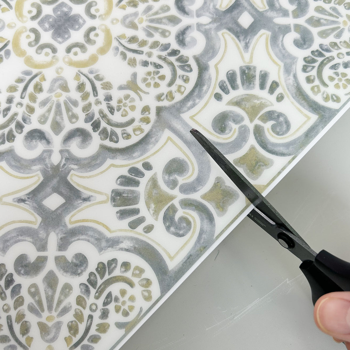 Decorative tile with a pattern being cut with scissors on a white background
