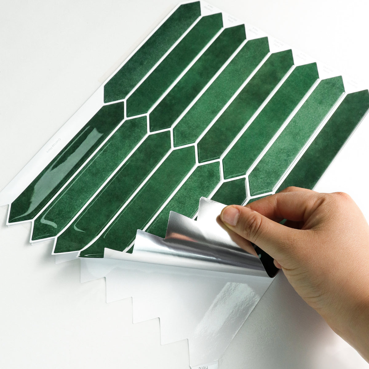 Green geometric tile stickers being peeled off the backing paper.