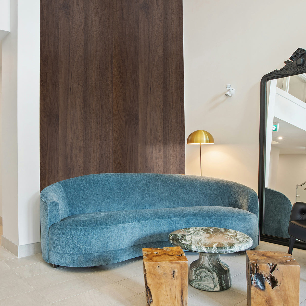 Blue curved sofa in a room with wooden and marble elements