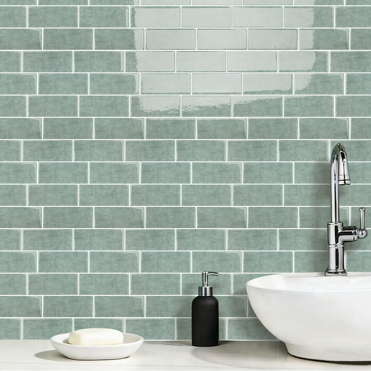 Bathroom with green tiled wall, white sink, and black soap dispenser.