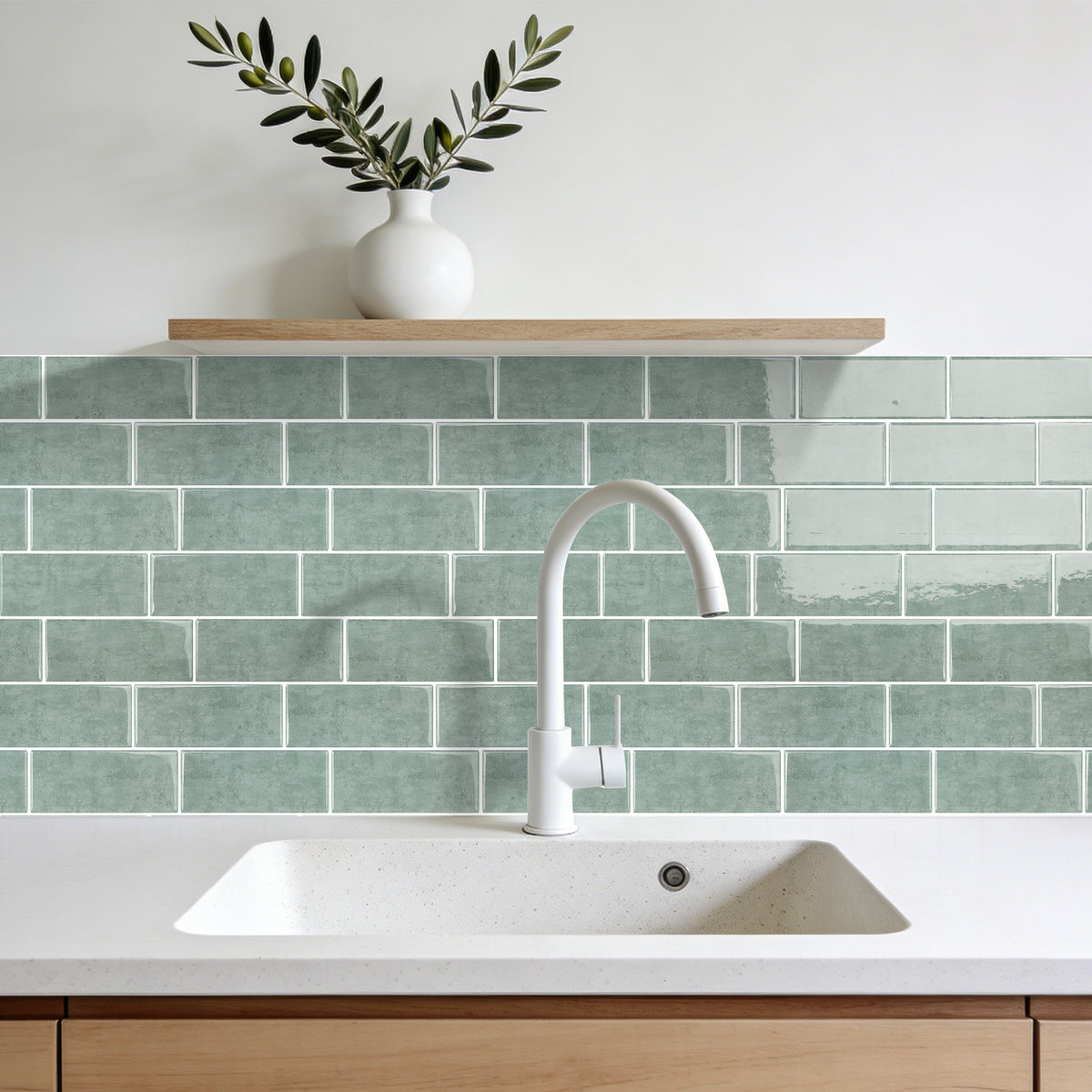 Kitchen with green tiled backsplash, white sink, and wooden shelf with a vase and plant.