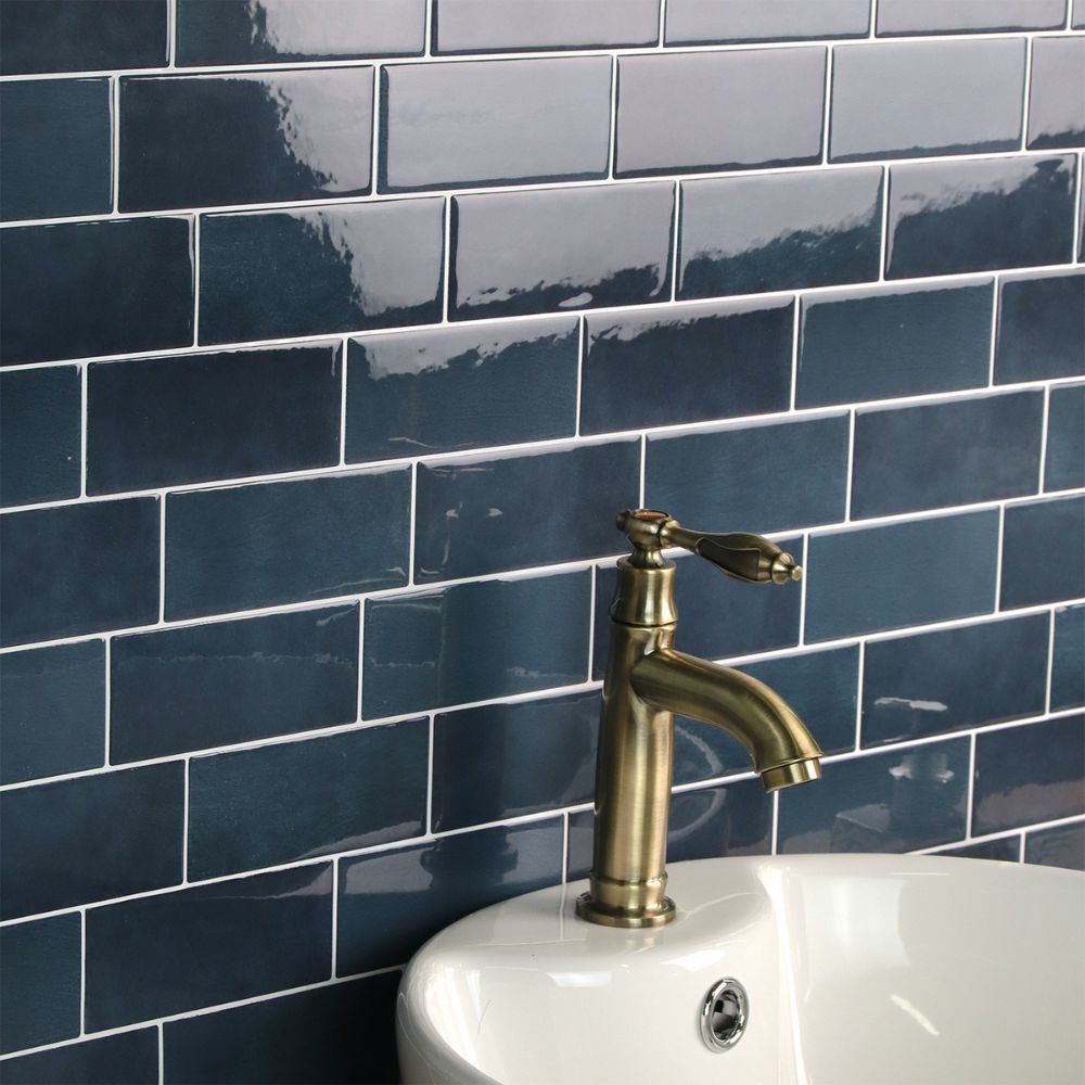Gold faucet on a white sink against a blue tiled wall