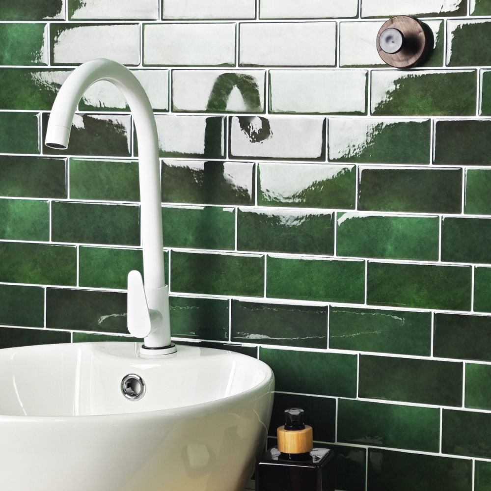 White sink with a faucet against a green tiled wall
