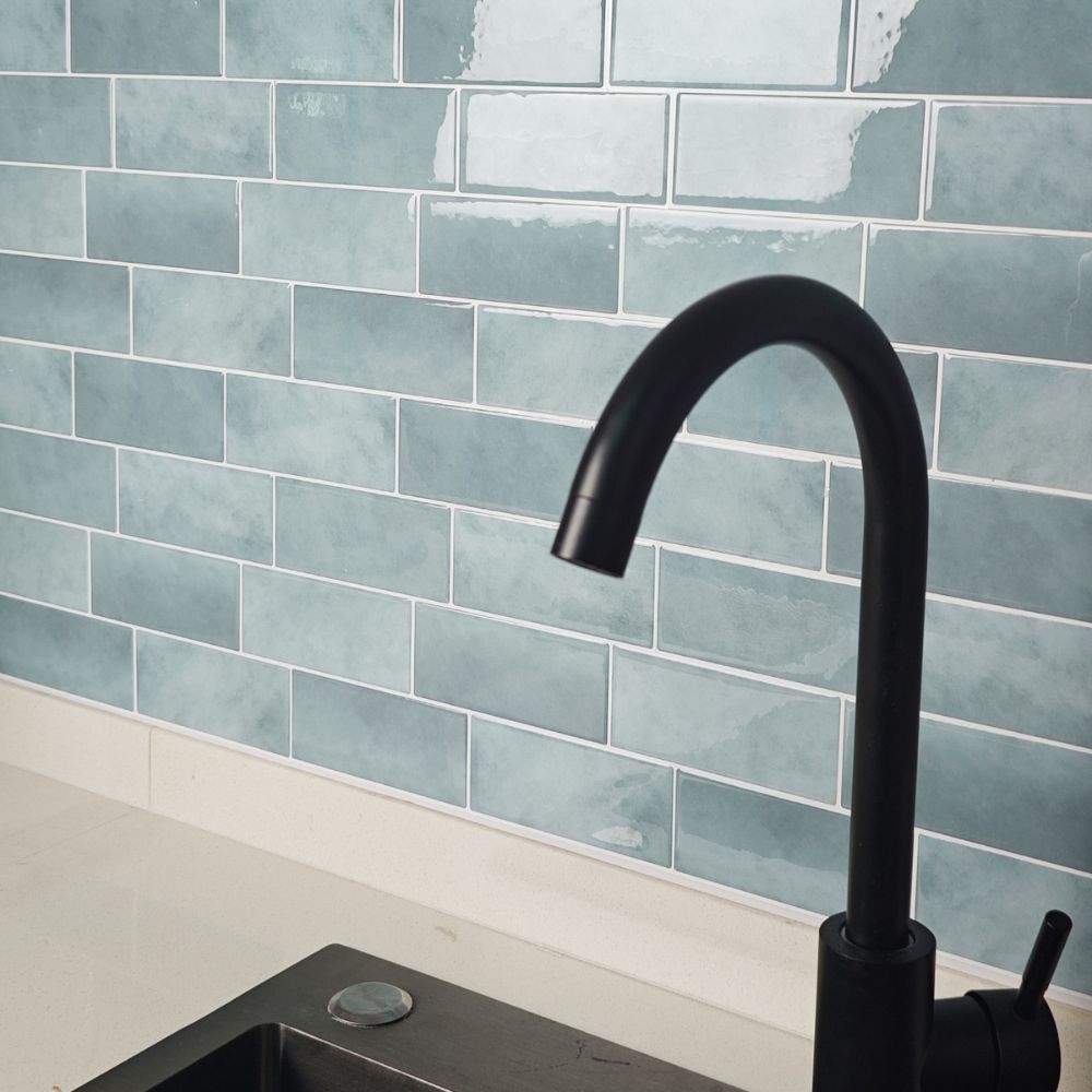 Black faucet against a blue tiled wall in a kitchen setting