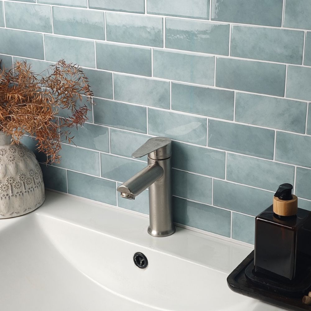 Bathroom sink with silver faucet against a tiled wall