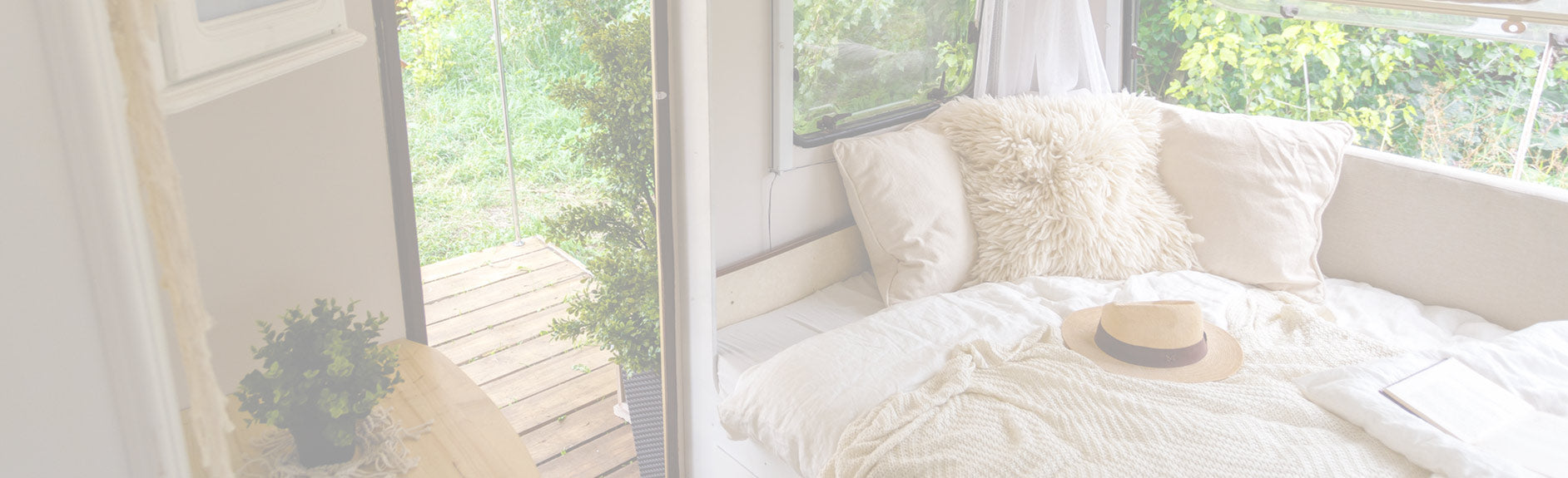 Bright sunroom with white window seat and white cushions and greenery outside the window