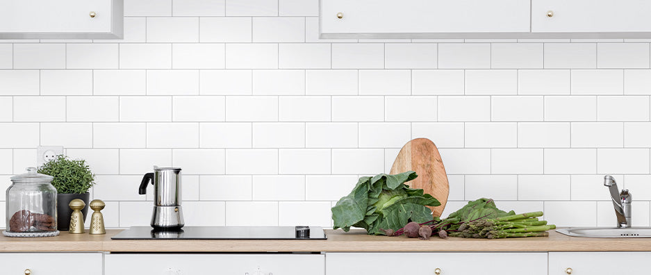 Kitchen with white subway tiles and grey grout splash back. Green groceries on wooden bench top
