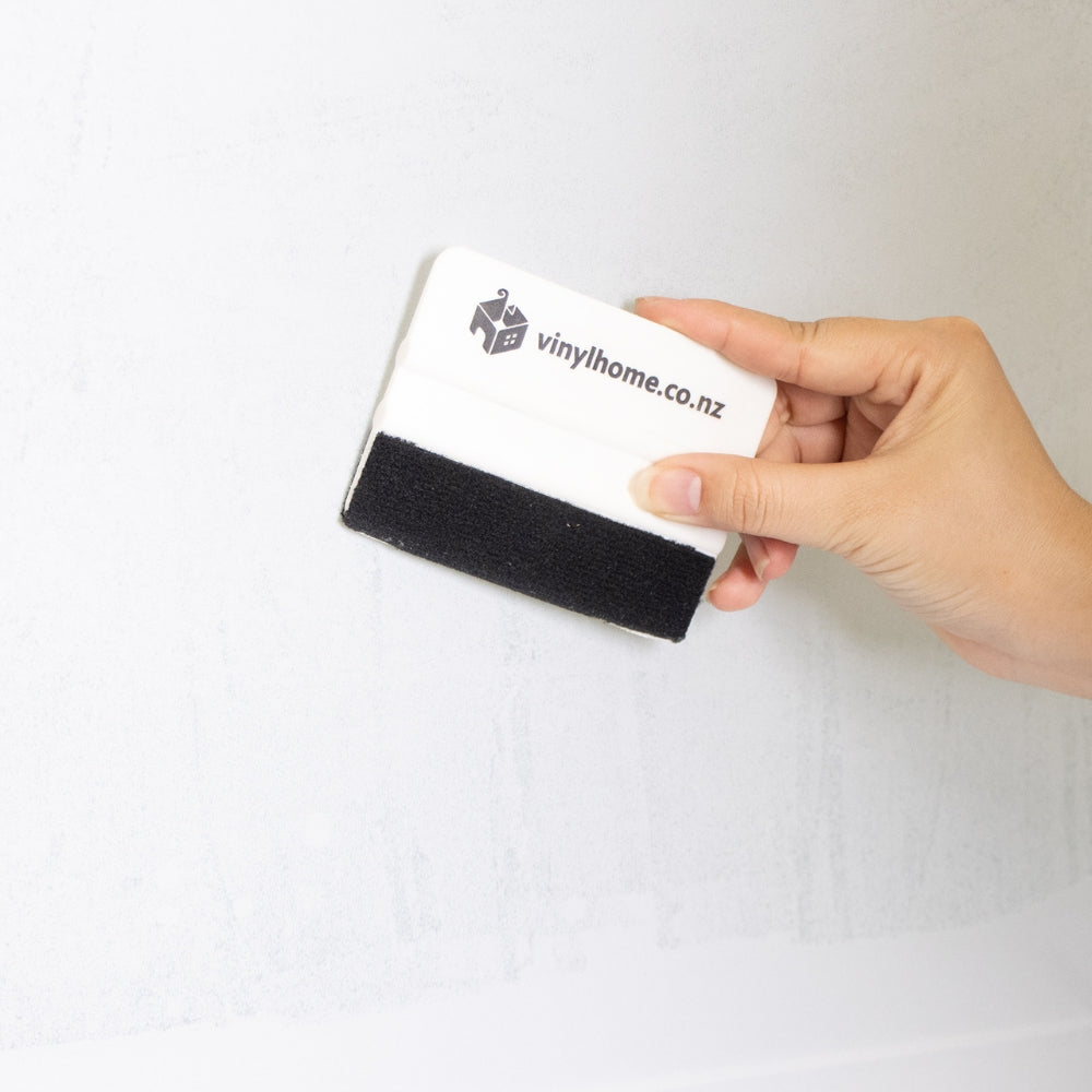 Modern bedroom with a large window film covered window, bed with blue pillows, and lamp.