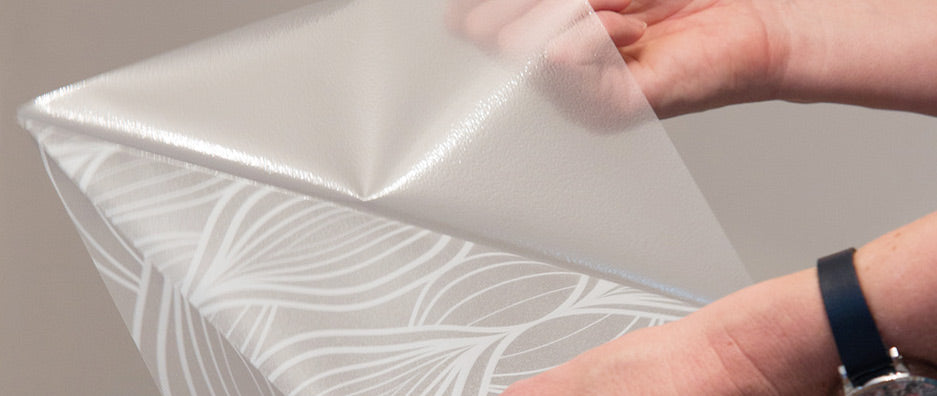 Close up of hands pulling backing paper apart from Charis static cling window film