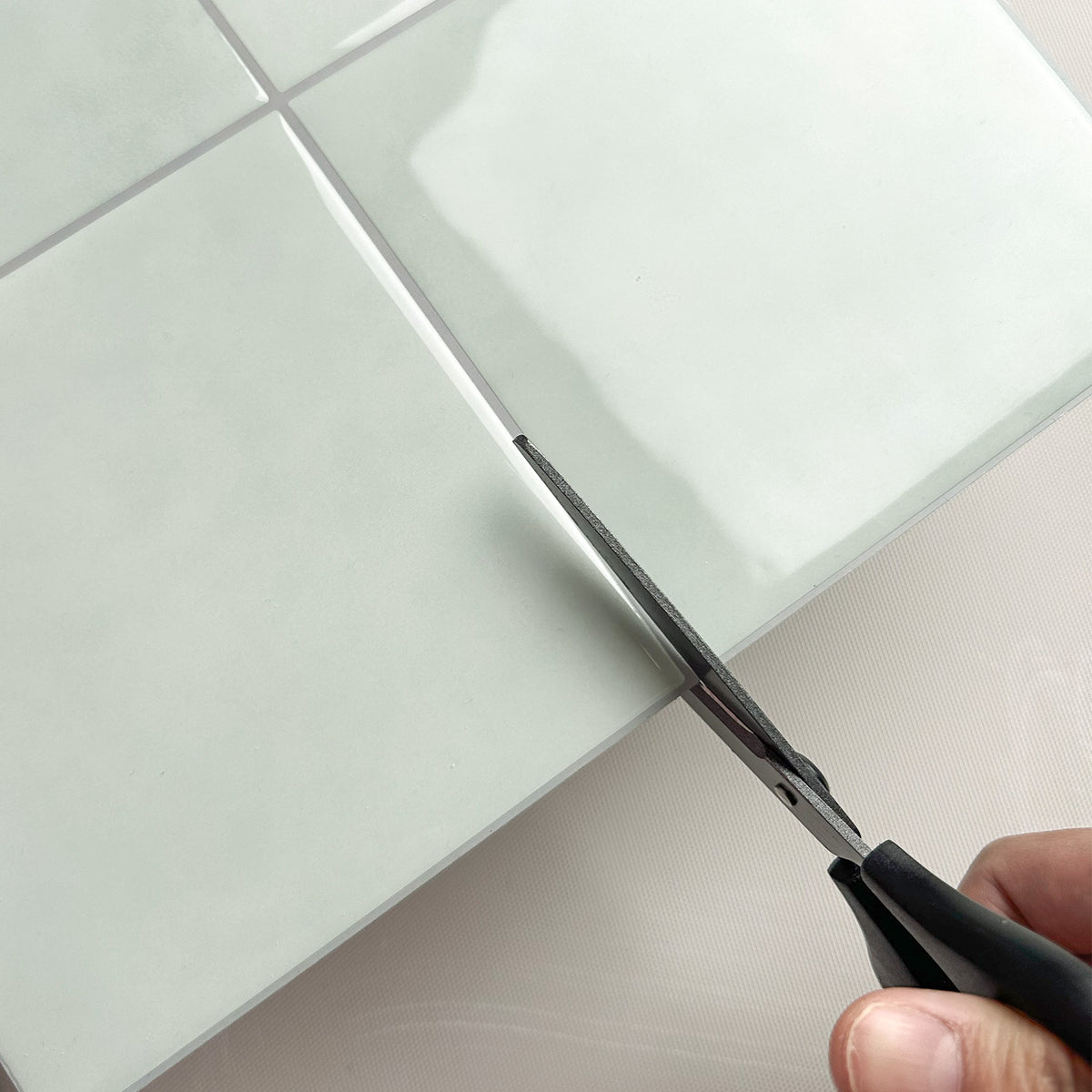 Person cutting peel and stick tiles with cissors