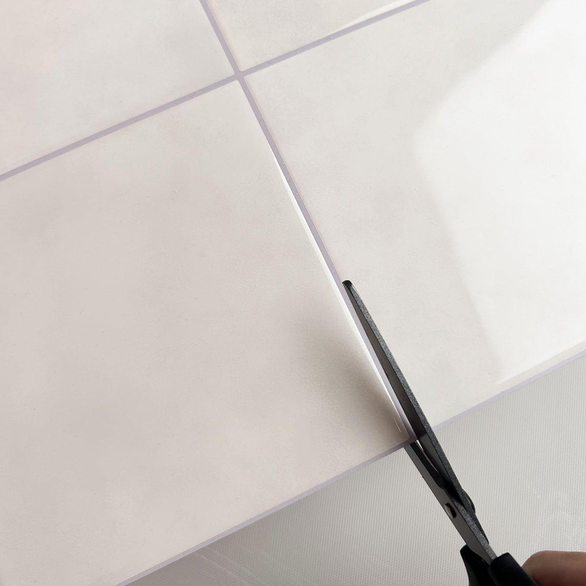 Scissors cutting a sand colouered tile.